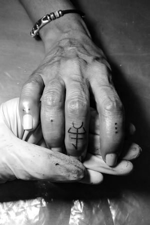 Tatuaje de puntos en los dedos y símbolo de Guerrero/a