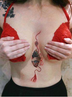 Fan with red strings in between her chest.The fan is decorated with cherry blossoms and mountain that holds her memory.#tattoo #norigaetattoo #fantattoo #peonytattoo #colortattoo #flowertattoo #tattooistsion