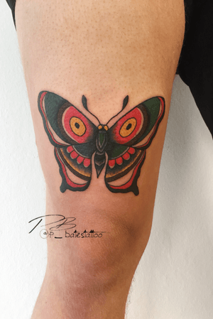 Get a timeless and vibrant traditional butterfly tattoo on your upper arm by skilled artist Patrick Bates.