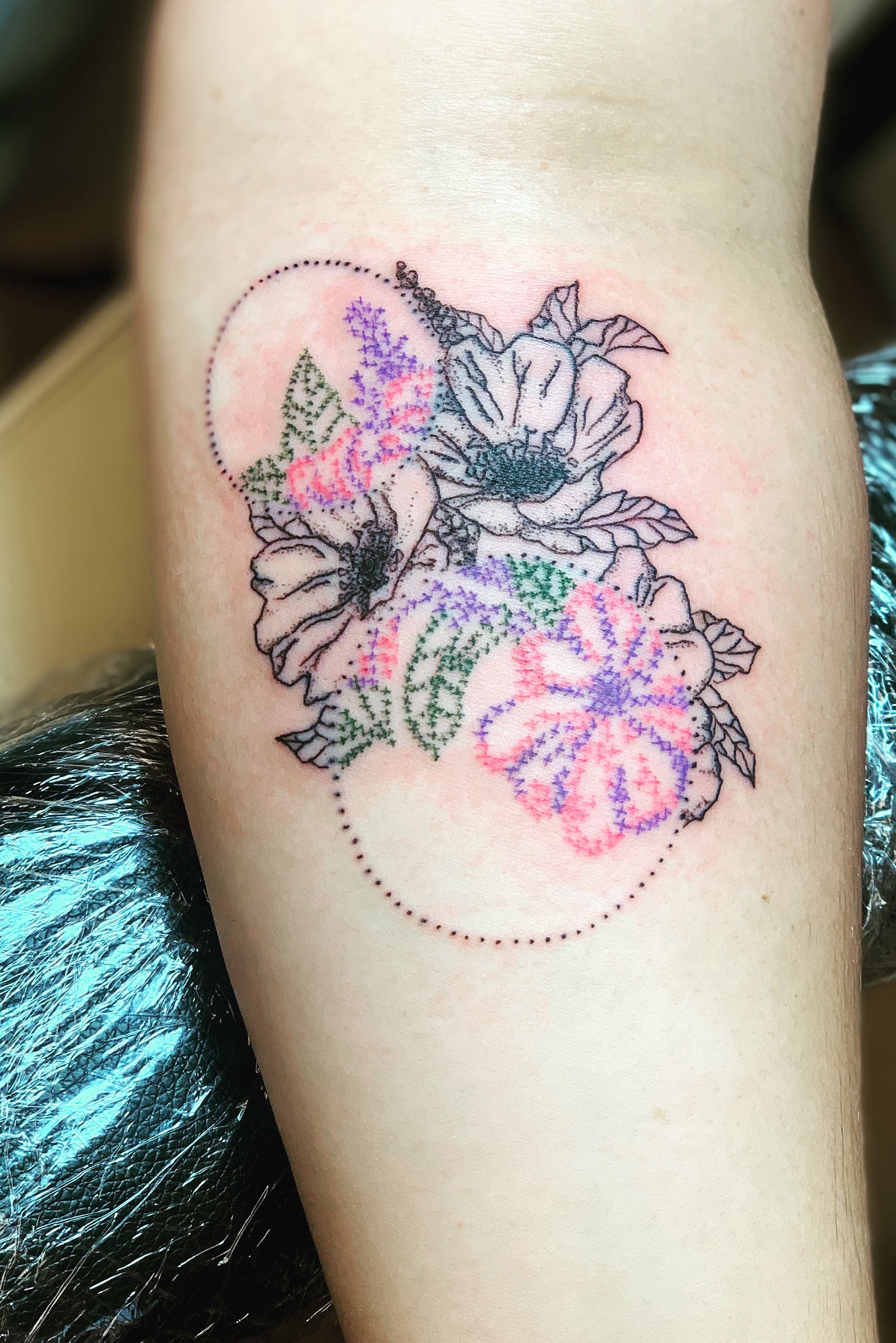 Cross stitch poppy tattoo on the right inner forearm