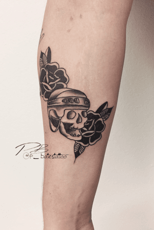 Get a striking forearm tattoo by Patrick Bates featuring a unique combination of flower, skull and helmet motifs.