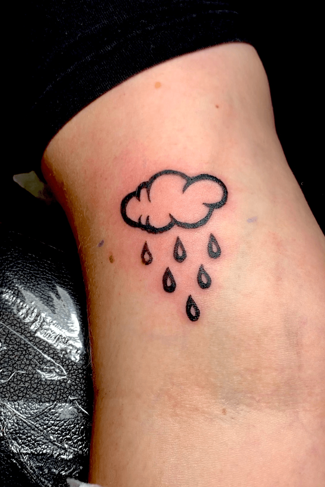 Fine line cloud and rain tattoo on the inner arm
