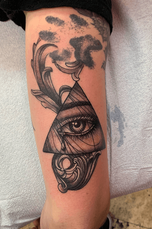 Black and grey all seeing eye with filigree on a tricep 