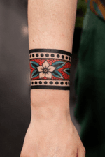 Traditional color floral arm cuff tattoo design. 2 inch thick horizontal wrist cuff with bright blue and red.
