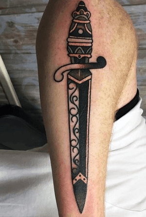 Traditional black large dagger design on outside of forearm.