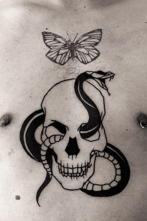 Traditional skull and snake outline design in black on client chest. 