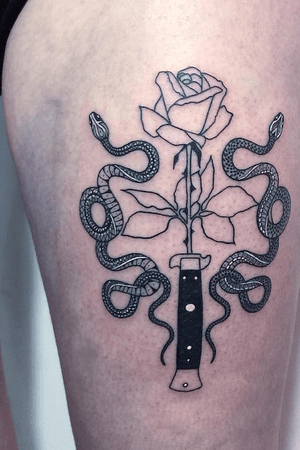 Thigh tattoo of traditional switchblade/rose design with 2 symmetrical snakes in black with white highlights large on clients thigh. 