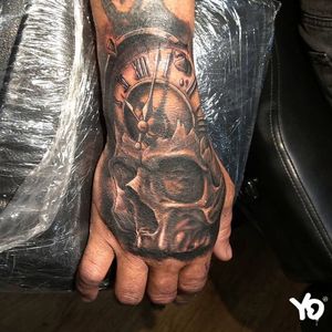 Black and grey realism skull and clock on hand