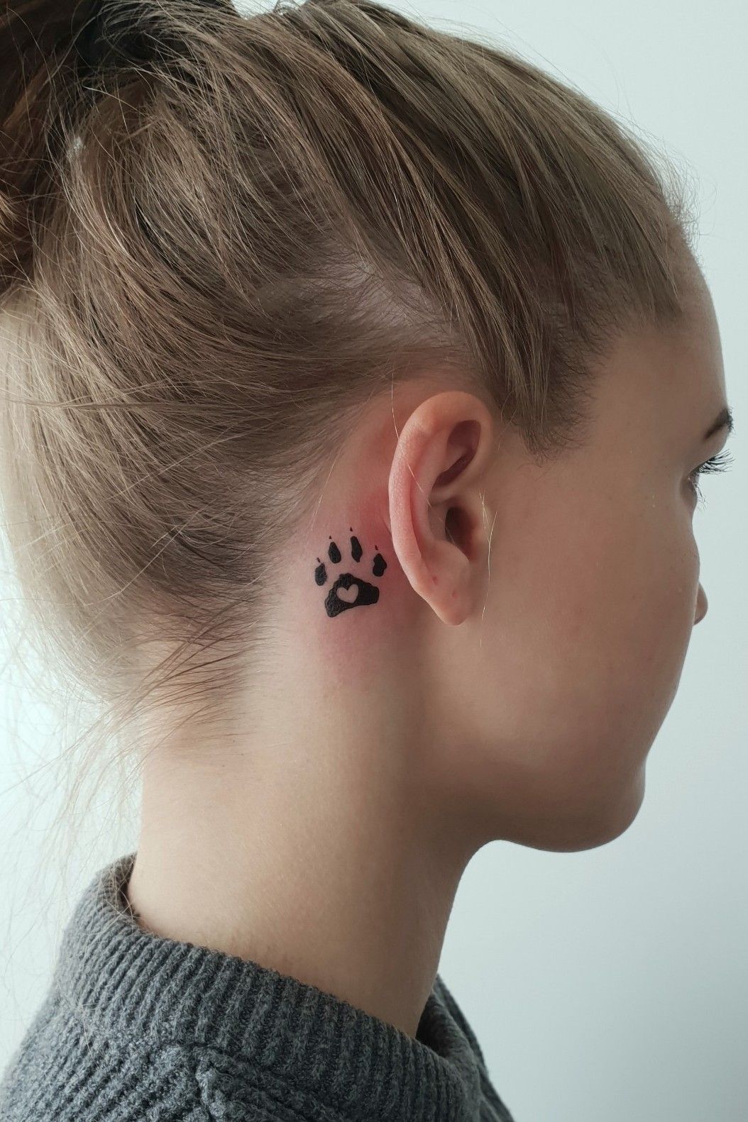 Minimalist dog paws tattoo on the ear