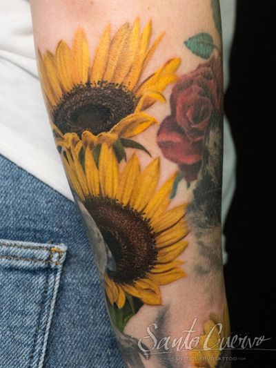 Beautiful sunflower tattoo on forearm by artist Alex Santo, blending realism and watercolor styles.