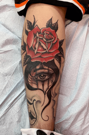 Traditional color rose and black and grey eye filler tattoo on a calf 