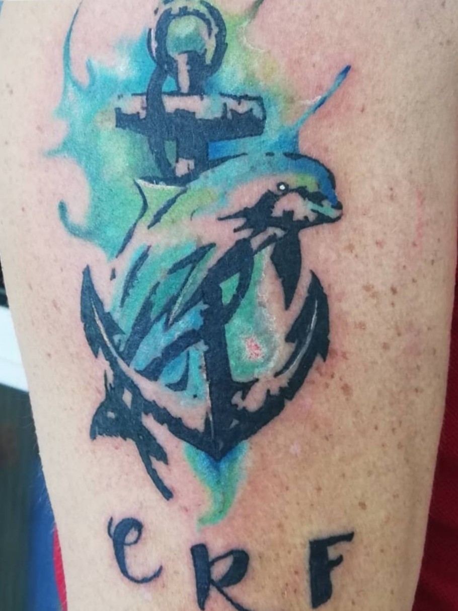 Anchor and dolphin tattoo on the tricep