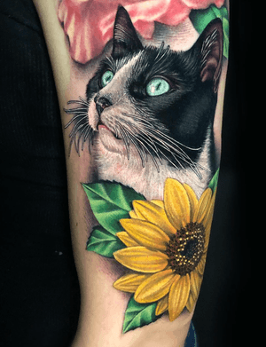 VerifiedDetails from this super cute black and white kitty and sunflower I tattooed recently at @gritnglory ?? I would normally add some more detail in the leaves, but wanted to match them to some already existing leaves around the above rose tattoo not done by me. I’m always excited to tattoo animals and flowers! #realism #realismcat #cat #cattattoo #sunflower