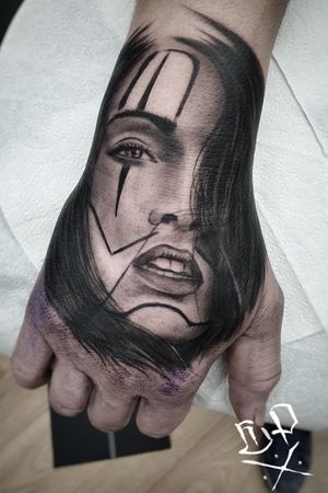 Get mesmerized by Mauro Imperatori's stunning black and gray realism tattoo of a woman and clown on your hand.