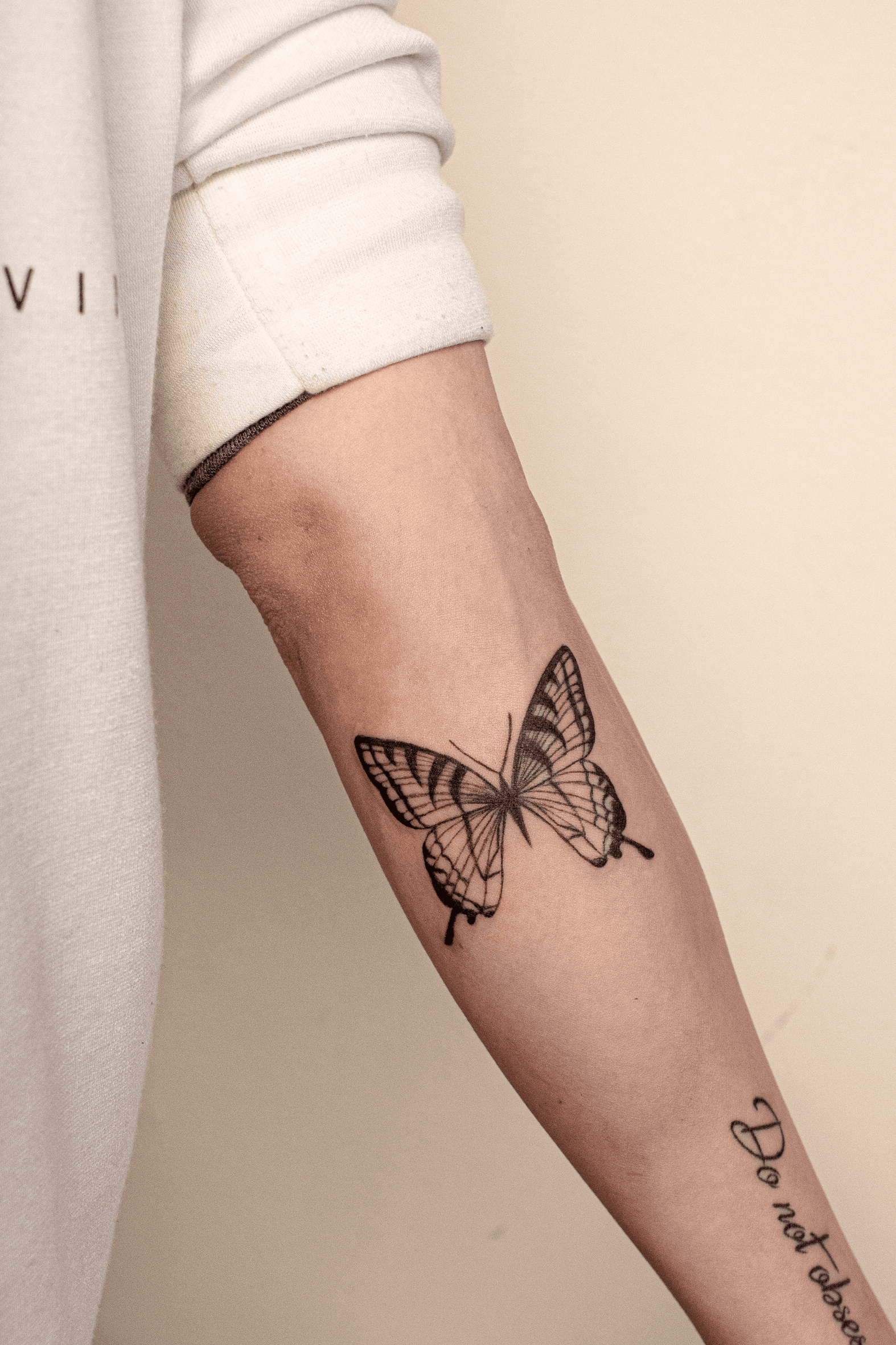 Fine line butterfly tattoo located on the triceo
