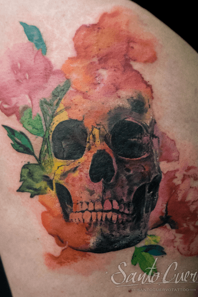 Vibrant watercolor skull tattoo on upper leg by talented artist Alex Santo, showcasing unique and creative design.