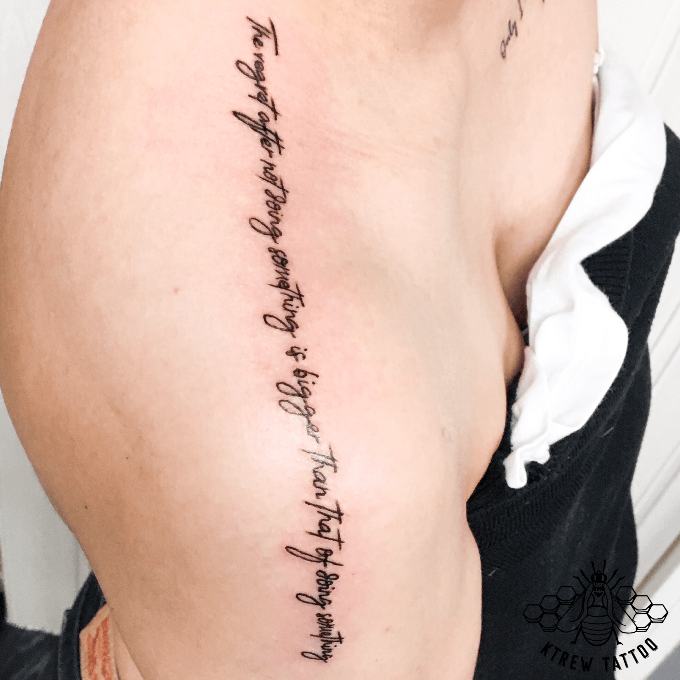 Lettering tattoo on top of shoulder