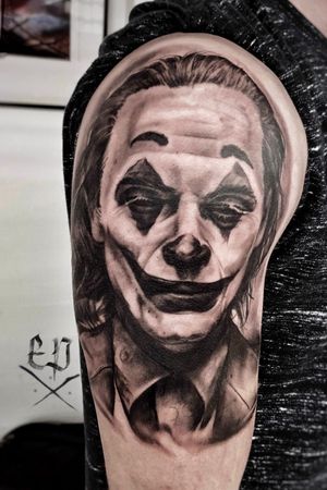 Get the iconic black and gray Joker portrait by Mauro Imperatori for a stunning realism tattoo on your upper arm.