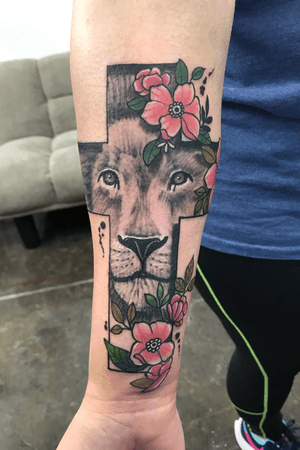 Cross with black and gray realistic lion image and color floral additions on inner forearm
