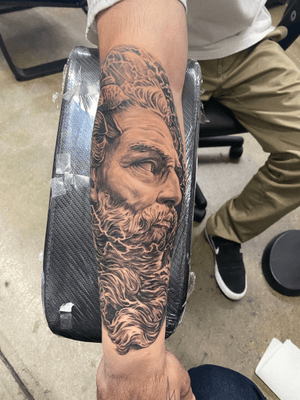 A captivating black and gray tattoo of a man with a beard, skillfully crafted by artist Jake Masri on the forearm.