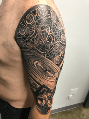 Unique blackwork tattoo by Jake Masri featuring a watch and DJ motif on the upper arm. Perfect for music lovers!