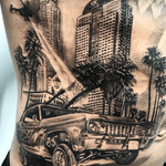 Stunning black and gray tattoo on ribs showcasing a realistic depiction of a building and car by artist Jake Masri.