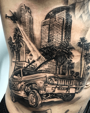 Stunning black and gray tattoo on ribs showcasing a realistic depiction of a building and car by artist Jake Masri.