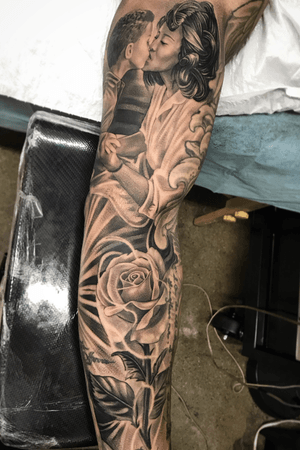 A stunning black and gray tattoo by Jake Masri featuring a mother and child with intricate flower detailing.