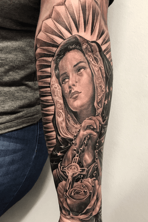 Stunning black and gray piece by Jake Masri featuring a woman shedding tears, intricately blending the motifs of flower and cross.