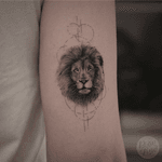 Small realistic lion-portrait with geometric Fineline elements on the back oft the upper arm.