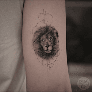 Small realistic lion-portrait with geometric Fineline elements on the back oft the upper arm.