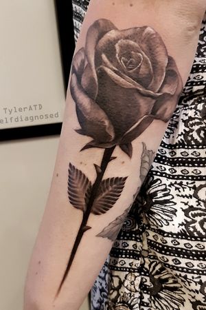 Realistic black and grey rose forearm tattoo.