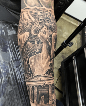 A stunning black and gray tattoo featuring a house, a woman, and the Parthenon, beautifully rendered on the forearm.