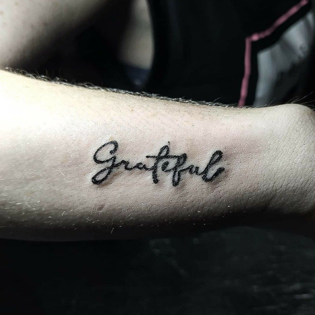 Grateful lettering tattoo on the inner forearm