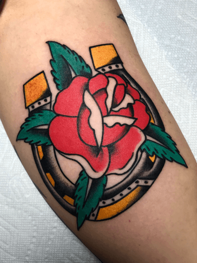 Beautiful traditional design by Felipe Reinoso, combining a vibrant flower with a lucky horseshoe on the arm.