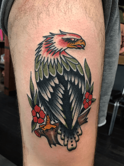 Traditional style tattoo on upper leg by artist Felipe Reinoso featuring a powerful eagle and delicate flower motif.