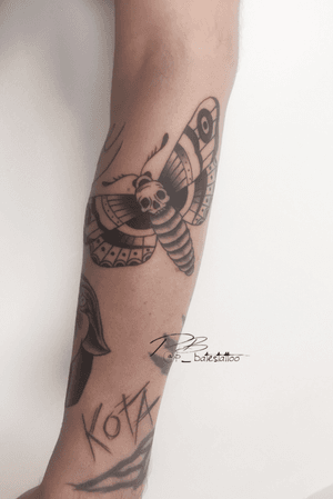 Traditional blackwork forearm tattoo featuring a moth and skull by Patrick Bates. Perfect mix of elegance and edge.