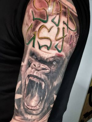 This black and gray tattoo on the upper arm features a majestic gorilla alongside a meaningful quote by Mauro Imperatori.