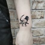 A striking black and gray tattoo of a bird and scythe by Jonathan Glick, perfect for the forearm.