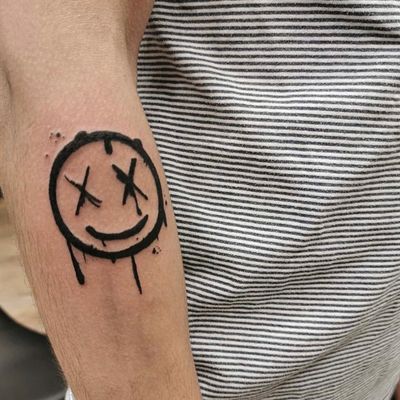 Vibrant new school forearm tattoo by Jonathan Glick featuring a cheerful smiley face pattern design.