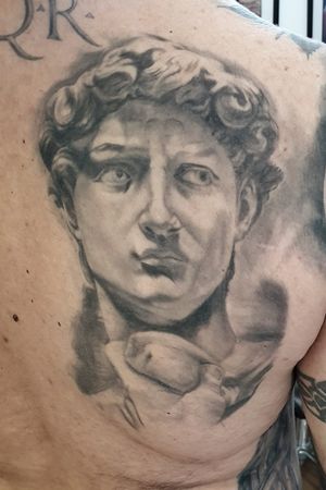 Capture the beauty of a realistic statue on your back with this stunning black and gray tattoo by Mauro Imperatori.