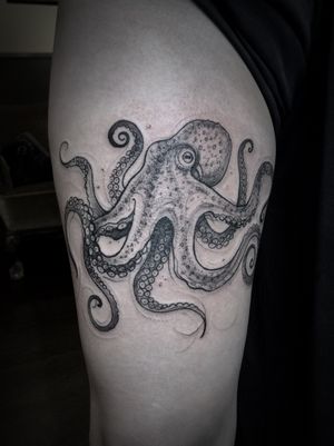 Aygul's stunning black and gray tattoo of an octopus gracefully swimming in the depths of the sea, located on the upper arm.