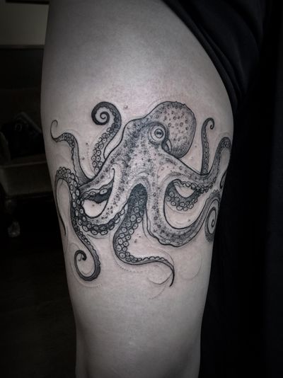 Aygul's stunning black and gray tattoo of an octopus gracefully swimming in the depths of the sea, located on the upper arm.