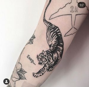 Unique knee tattoo featuring small lettering and an illustrative tiger design by Federico Colantoni.
