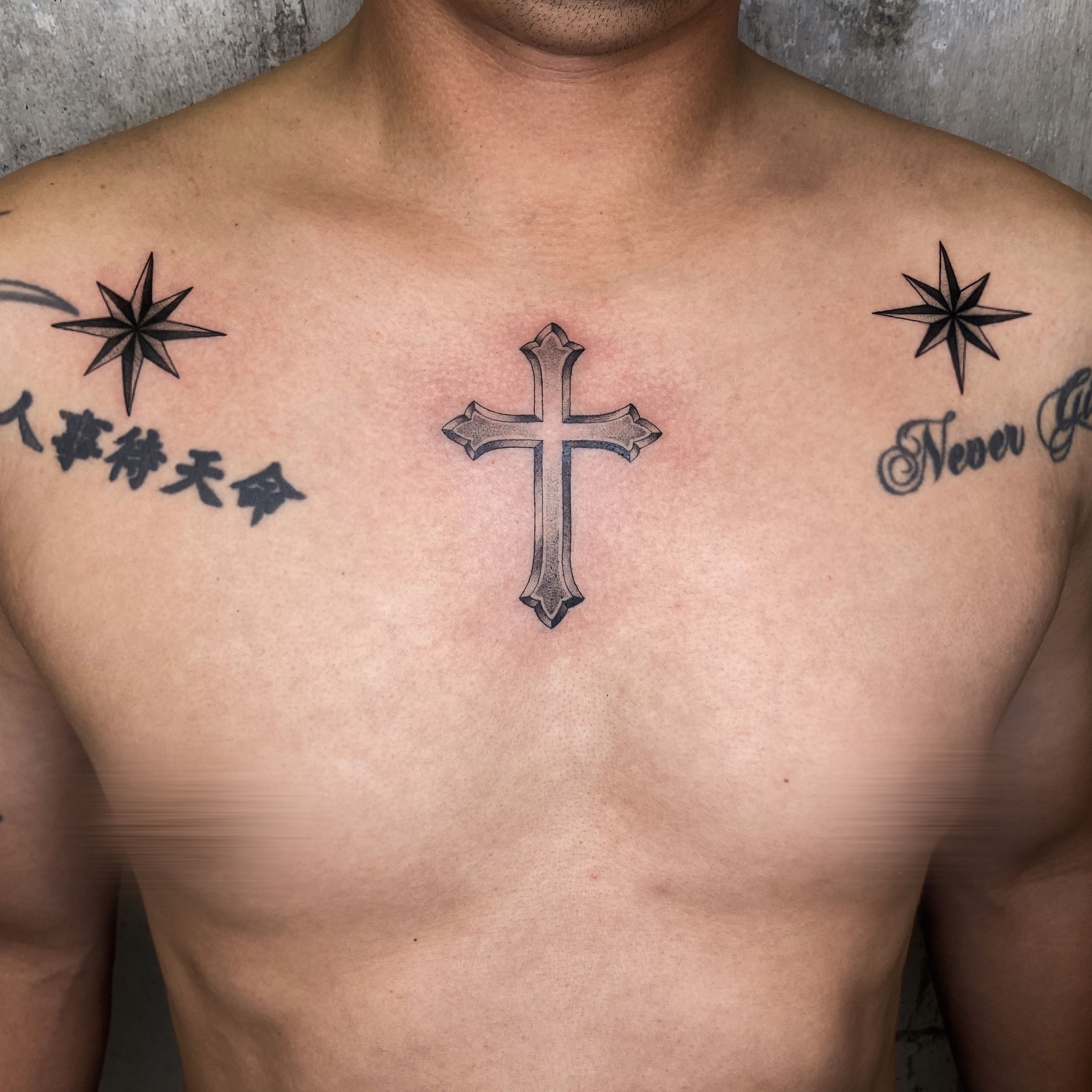 Grey shaded cross with crown tattoo on left upper chest for men