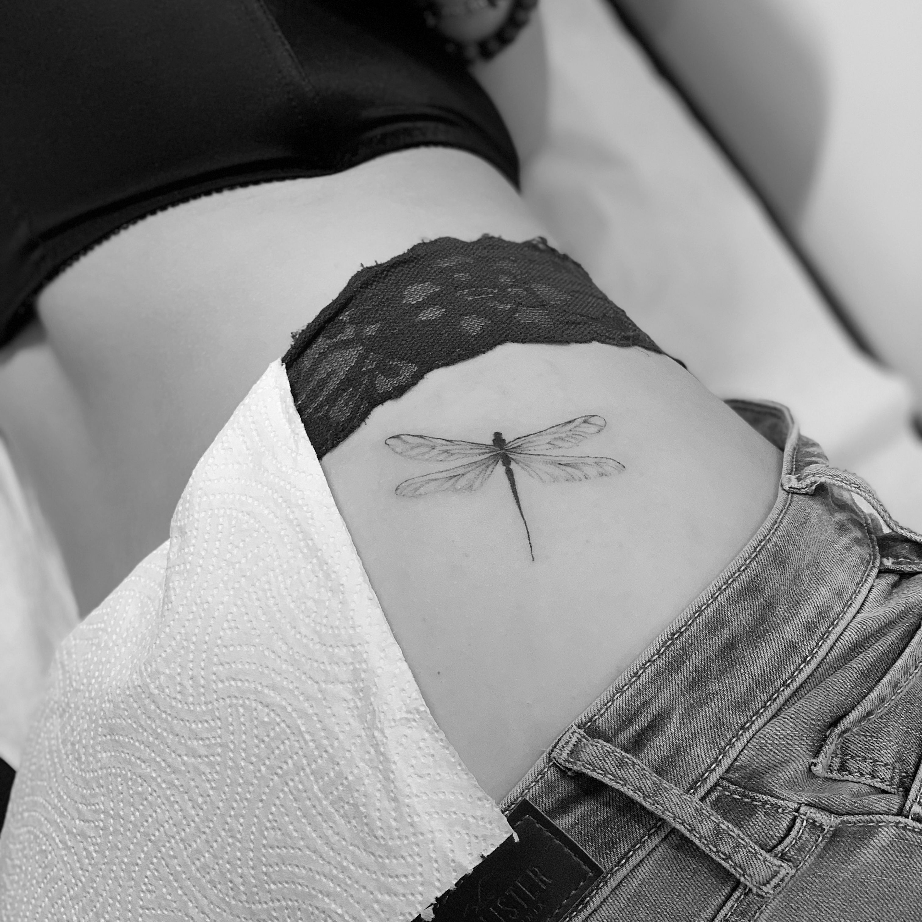 Single needle dragonfly tattoo on the forearm
