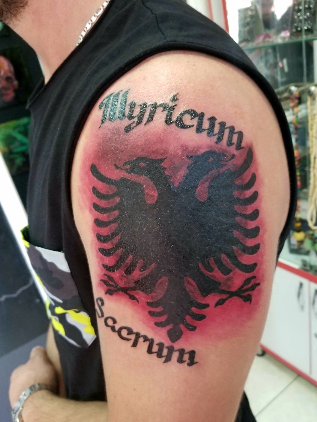 An Albanian double headed eagle Tattoo in a modern style with a banner by  the feet that says my last name 