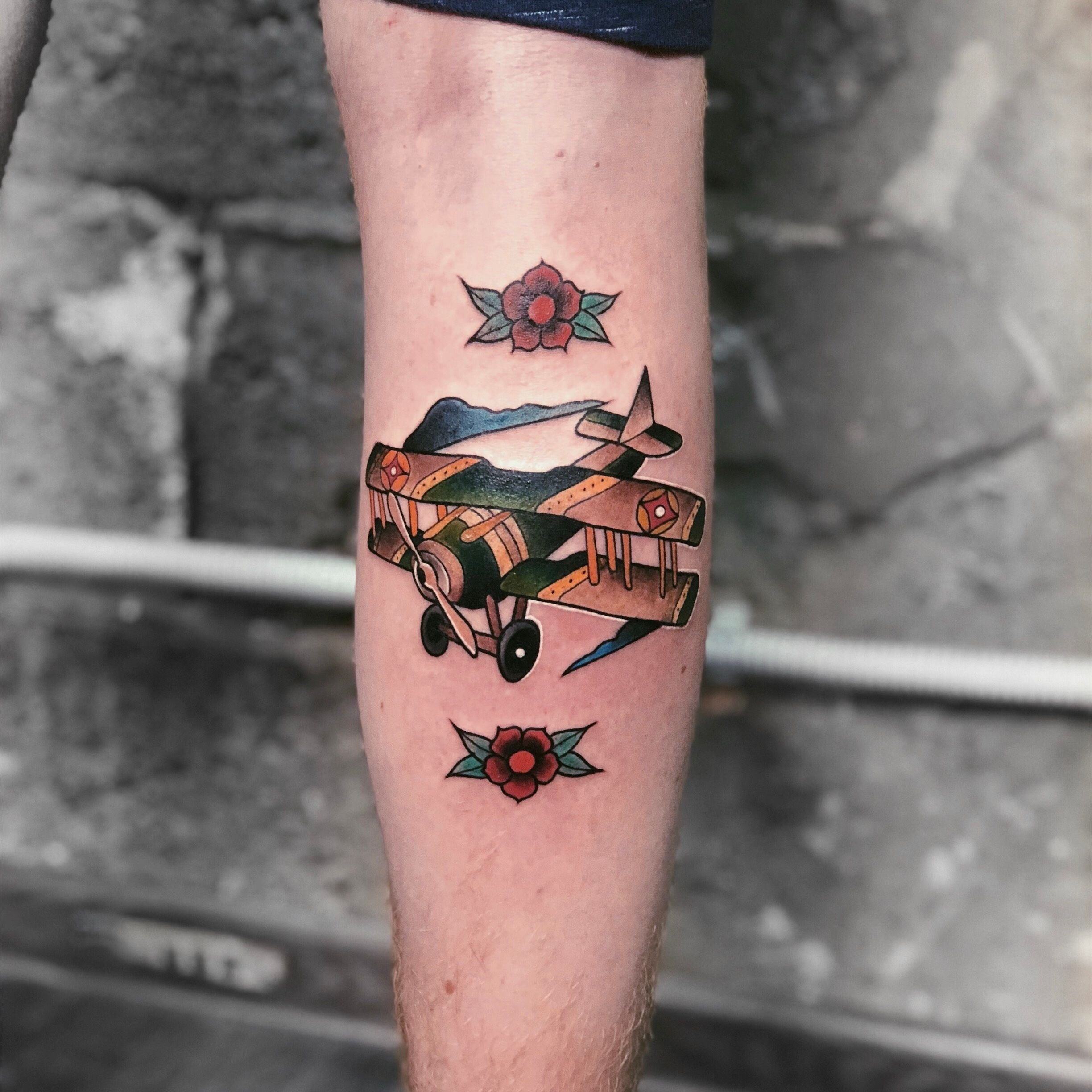 Minimalist paper airplane tattoo on the upper arm