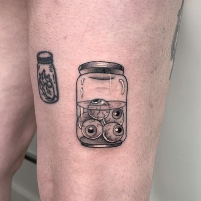 Express your style with a bottle, eyes, and eyeballs tattoo on your upper leg by the talented artist Galen Bryce (aka Drip Skull).