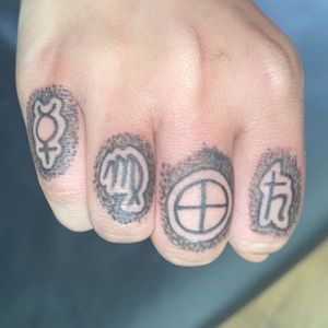 Symbols for (from pinky to pointer finger/left to right) Saturn, Virgo, Earth, and Mercury.